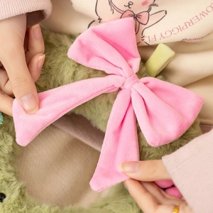 Detailed close-up showing soft plush texture of the green pet accessory with pink bow