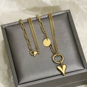 Detail of layered gold stainless steel necklace with heart pendant and paperclip chain