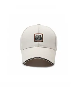 Gros plan sur la casquette beige avec écusson vintage marron et bordure lettrée