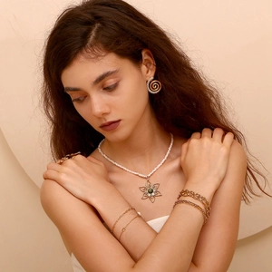 Detail showing elegant gold-plated paperclip chain bracelet and flower charm on model