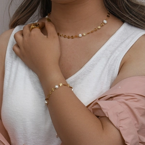 Close-up of golden necklace and bracelet set with freshwater pearls and snowflake charms