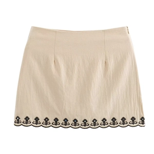 Detailed close-up of beige mini skirt with black floral embroidery and blue beadwork