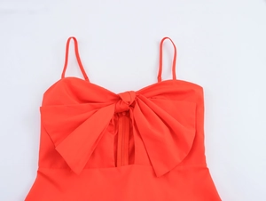 Close-up of a red dress bodice featuring a large decorative bow and a center zipper detail