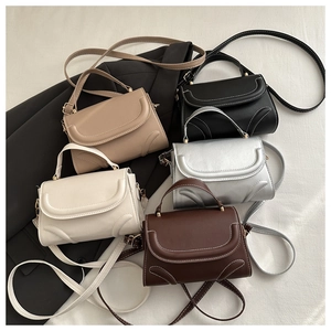 Detail of square handbags with decorative curved stitching and light gold metal hardware