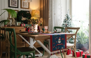 Detail of Christmas table runner featuring snowman reindeer motifs and red fringe tassels