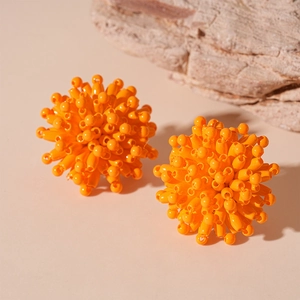 Detailed view of orange sphere stud earrings with a 3D radial bead design