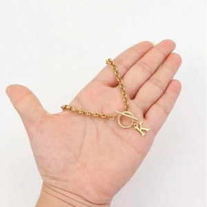 Gold letter K charm bracelet with round link chain and toggle clasp on hand