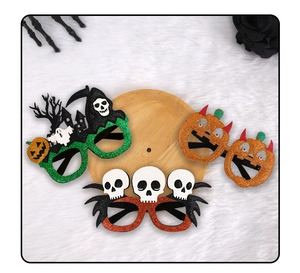 Glittering Halloween party glasses with pumpkin, grim reaper, and skull designs on plush