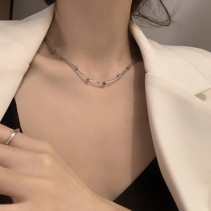 Detail of a minimalist double-layer titanium steel necklace with square pendant beads