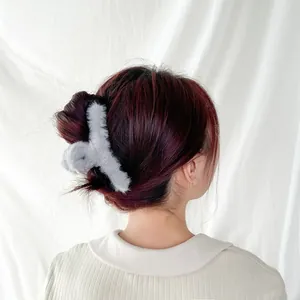 Detailed view of light grey plush hair claw clip styled on dark reddish-brown hair