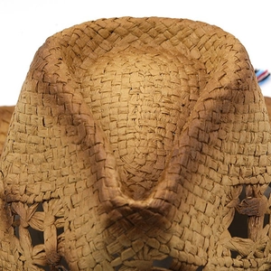 Detailed macro view of brown woven straw hat showing texture and hollow out pattern