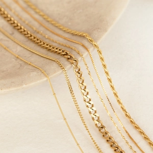 Macro shot of gold-plated stainless steel chains including Cuban, snake, and rope styles