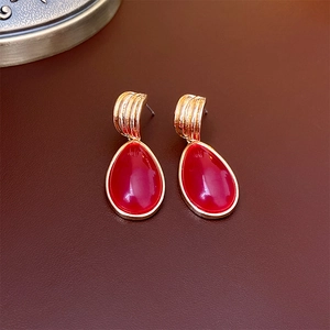 Detail view of vintage gold earrings featuring large oval red gemstones on brown leather