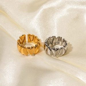 Detailed view of gold and silver heart-shaped open rings on a luxury silk backdrop