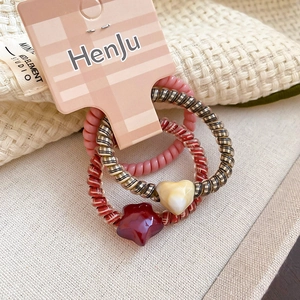 Three spiral hair ties with heart and star charms on a branded display card
