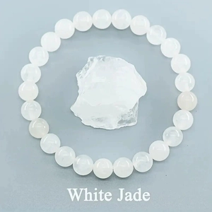 Macro shot of 8mm white jade bead bracelet on raw mineral stone for jewelry detail