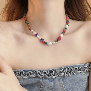 Close-up of bohemian beaded necklace with colorful stones and pearls on a model wearing denim