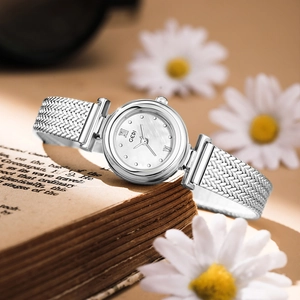 Silver women's quartz watch with pearl white dial and metal woven strap on a book