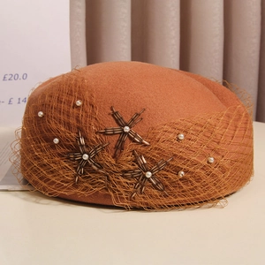 Detail of camel wool beret featuring mesh bow and elegant pearl star embroidery