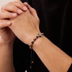 Bracciale di perle occhio di tigre ed ematite con ciondolo a croce al polso maschile