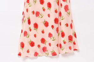 Close-up of pink floral sleeveless dress featuring red rose print and neat hemline details