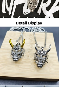 Detail of vintage Hannya mask pendant in silver and gold tones with bead chain necklace
