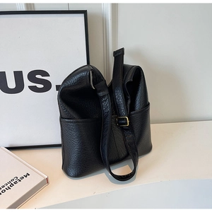 Détail du sac seau en cuir noir grainé avec boucle dorée et bandoulière réglable