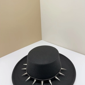 Close-up of black wool felt flat top hat decorated with sharp punk silver metal spikes.