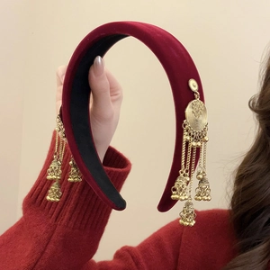 Detail of red velvet headband featuring golden metal jhumka tassel earrings