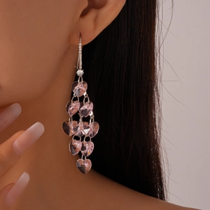 Gros plan de boucles d'oreilles cœur en cristal rose avec finition argentée sur un modèle