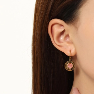 Close-up of pink resin gemstone earrings with vintage gold filigree hollow design