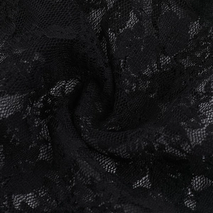 Dettaglio del top in pizzo nero con intricati motivi floreali e trama a rete fine