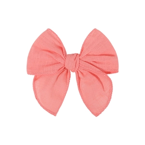 Handmade coral pink linen bow hair clip for children with textured fabric and stitched edges