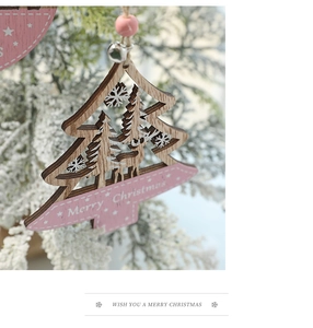 Detail of pink wood Christmas tree ornament with reindeer carving and silver bell