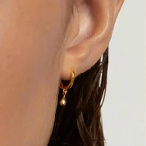 Close-up of elegant gold teardrop earrings worn by a model with wet hair styling