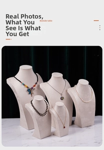 Beige velvet bust display stands for necklaces with diverse jewelry on marble surface