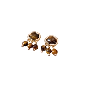 Vintage gold earrings with brown stone oval pendants and dangling beads on white backdrop