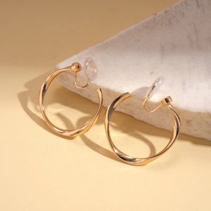 Detail view of twisted gold metal clip-on earrings with comfortable silicone pads on stone