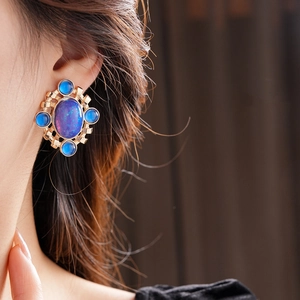 Macro shot of gold vintage earrings featuring an oval blue gemstone and intricate metalwork