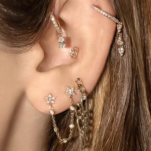 Rose gold geometric earring set with stars and zircons worn on a model's ear