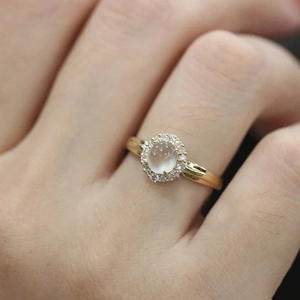 Elegant gold ring featuring an oval moonstone centerpiece with a diamond halo on finger