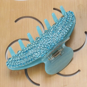 Macro detail of large hair claw clip with dense blue rhinestones and metal spring