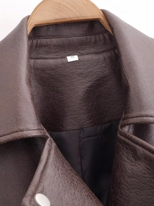Close-up of brown PU leather jacket collar and shoulder with a sewn-in size S label