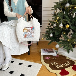Detail of white quilted tote bag featuring a cute cartoon embroidery and braided handles