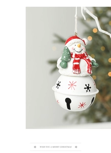 Close-up of snowman doll with iron bell on Christmas tree with warm festive lighting