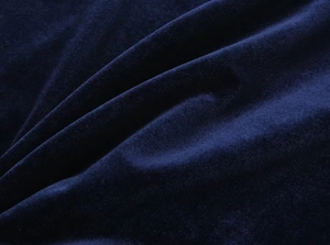 Macro shot of dark blue velvet fabric texture with soft plush sheen and elegant drapes