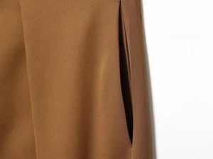 Detailansicht der versteckten Seitentasche der braunen High-Waist-Plissee-Ballonhose