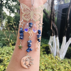 Detail of metal butterfly and moon crystal suncatcher with blue stones and solar motifs