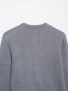 Dettaglio maglione in maglia grigia a girocollo che mostra la texture morbida e le cuciture