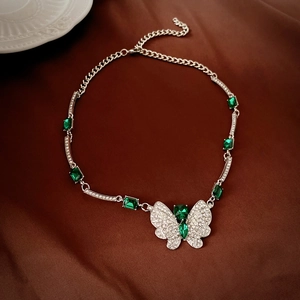 Detail of butterfly necklace with emerald green crystals and sparkling zircons on leather